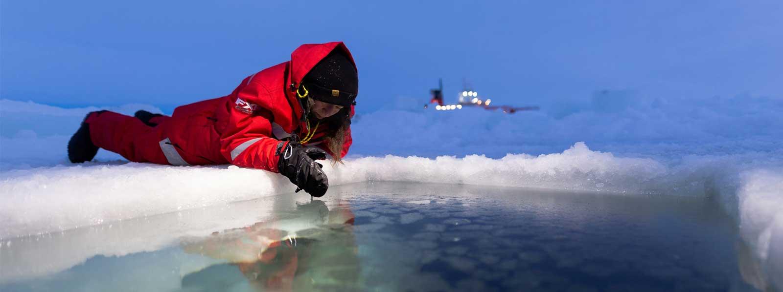 Person auf dem Eis liegend, im Hintergrund die Polarstern